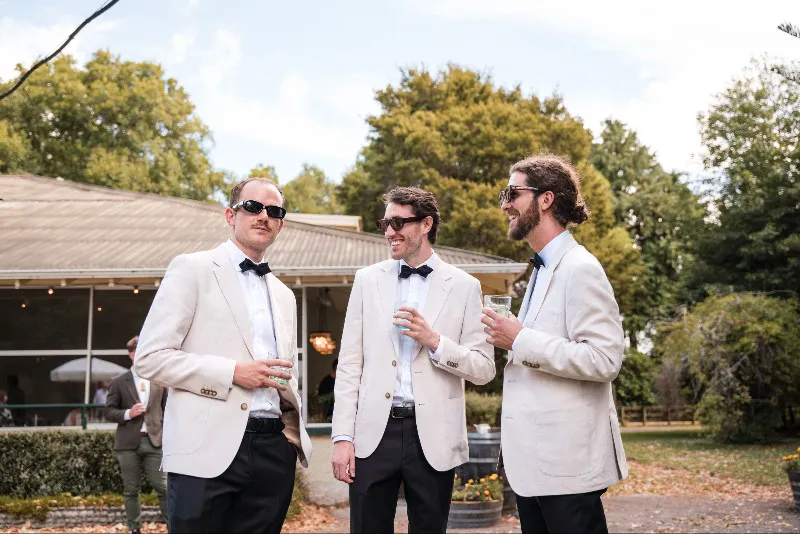 Groomsmen in white dinner jackets laughing together